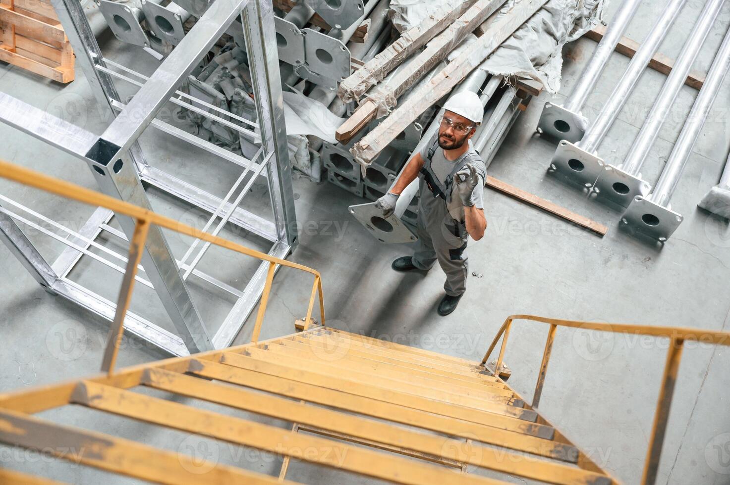 Climbing ,up on the ladder. Young factory worker in grey uniform photo