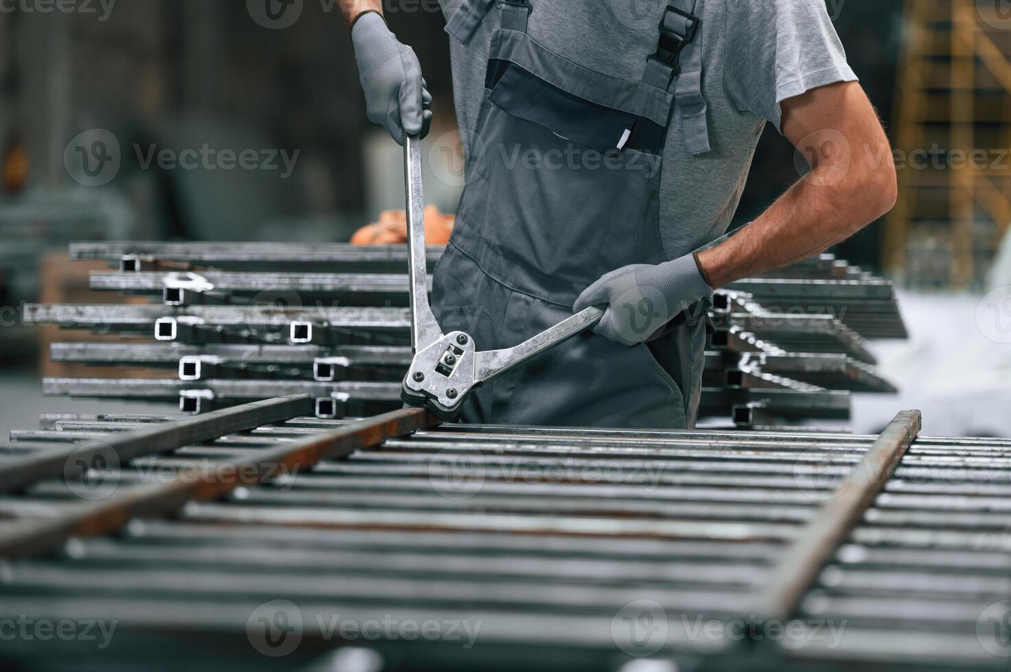 Using the clippers to cut the metal product. Close up view of man that is working at the factory photo