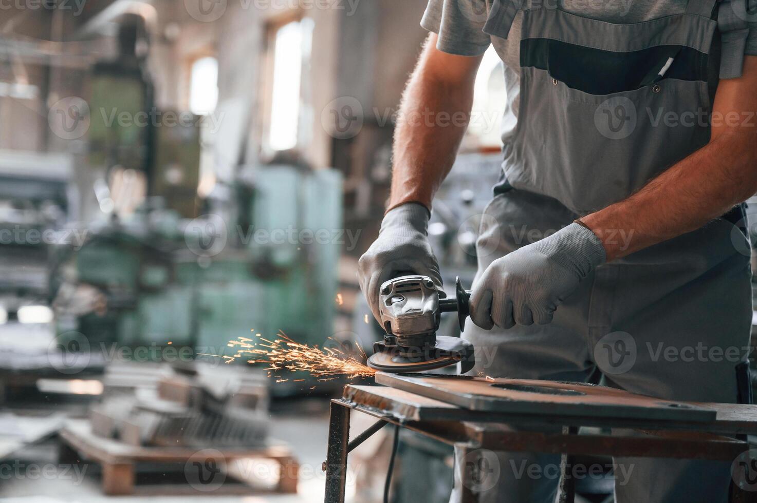 Polishing the surface with, angle grinder. Close up view of man that is working at the factory photo