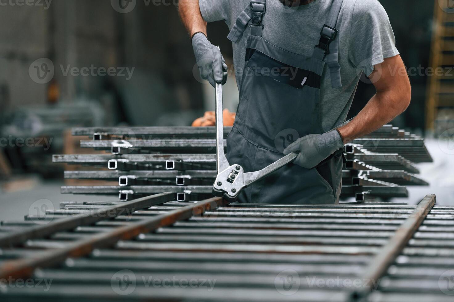 Using ,the, clippers to cut the metal product. Close up view of man that is working at the factory photo