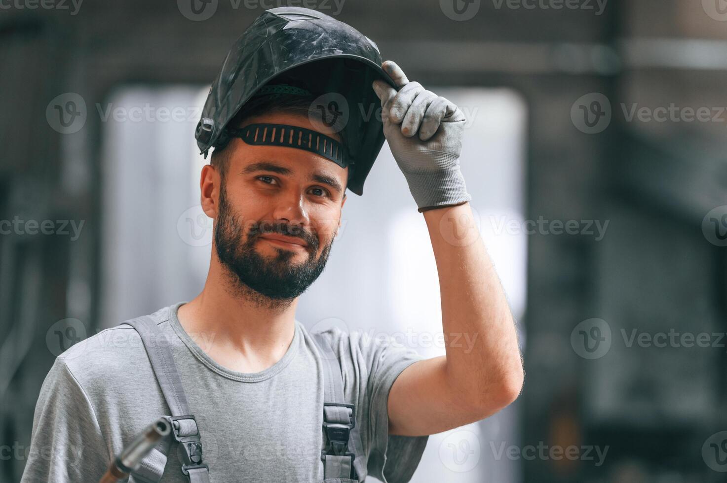 Welder man in safety,, helmet. Young factory worker in grey uniform photo