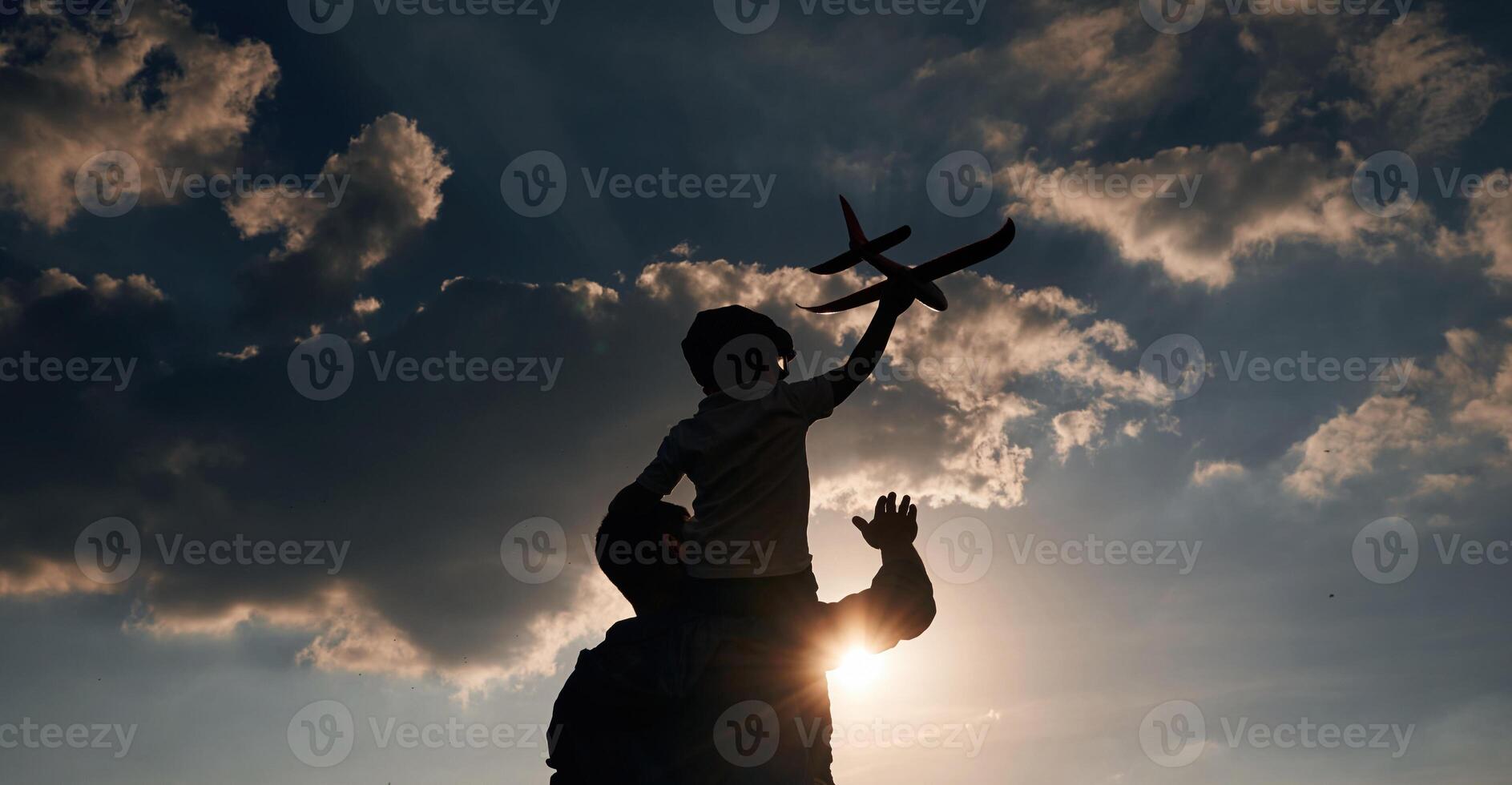 Against dramatic sky, with toy plane, sitting on shoulders. Father and little son are playing and having fun outdoors photo