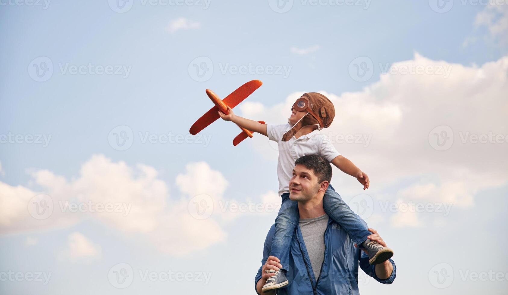 Sitting, on shoulders,, playing with toy plane. Father and little son are having fun outdoors photo