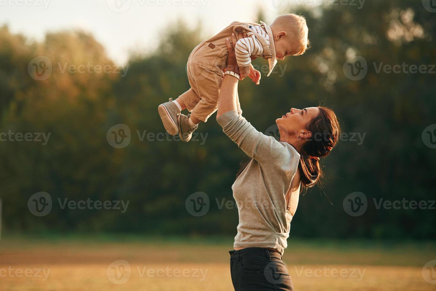 Holding kid in hands. Mother ,is ,with her little baby son are outdoors together photo