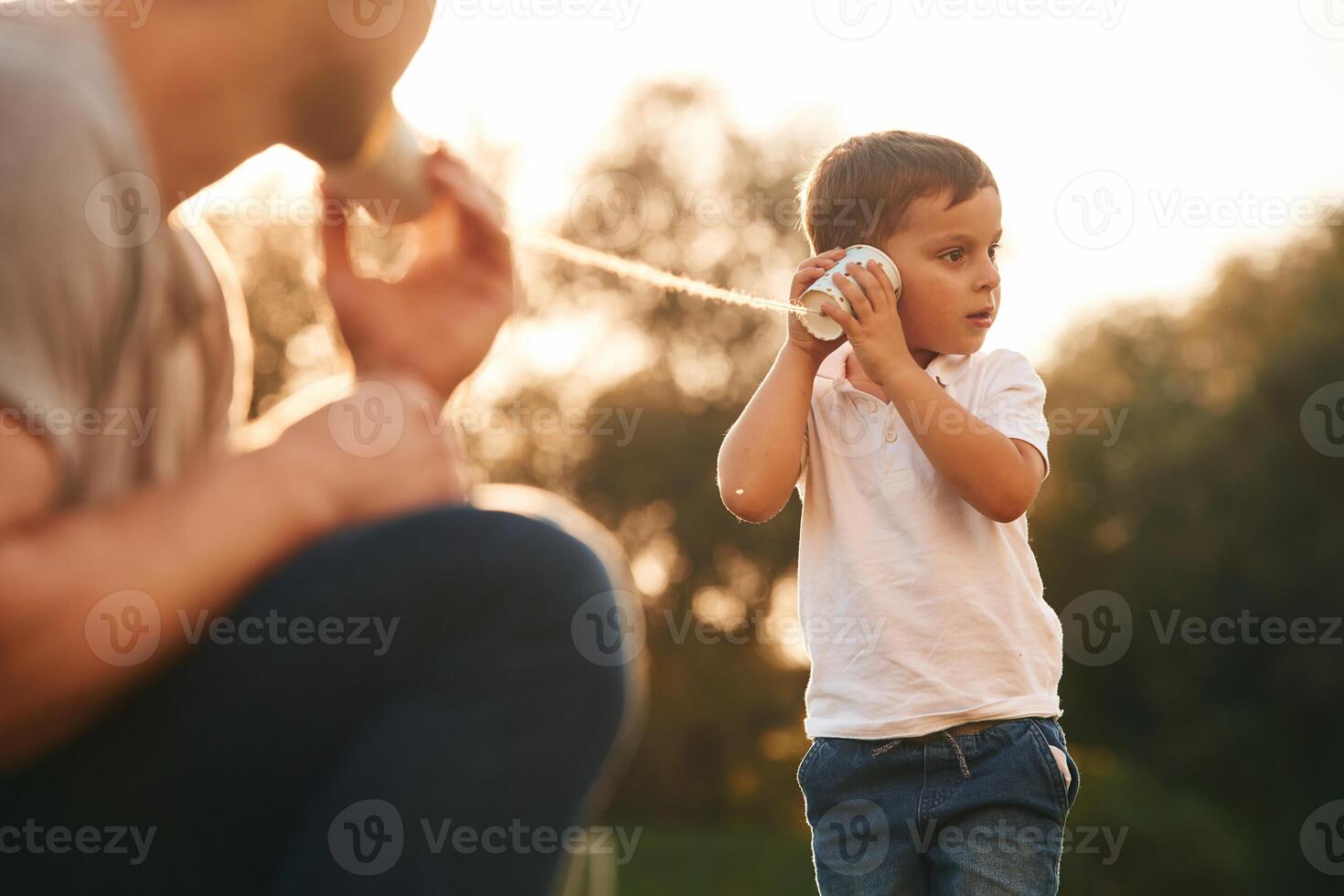 With string can phone. ..Father and little son are playing and having fun outdoors photo