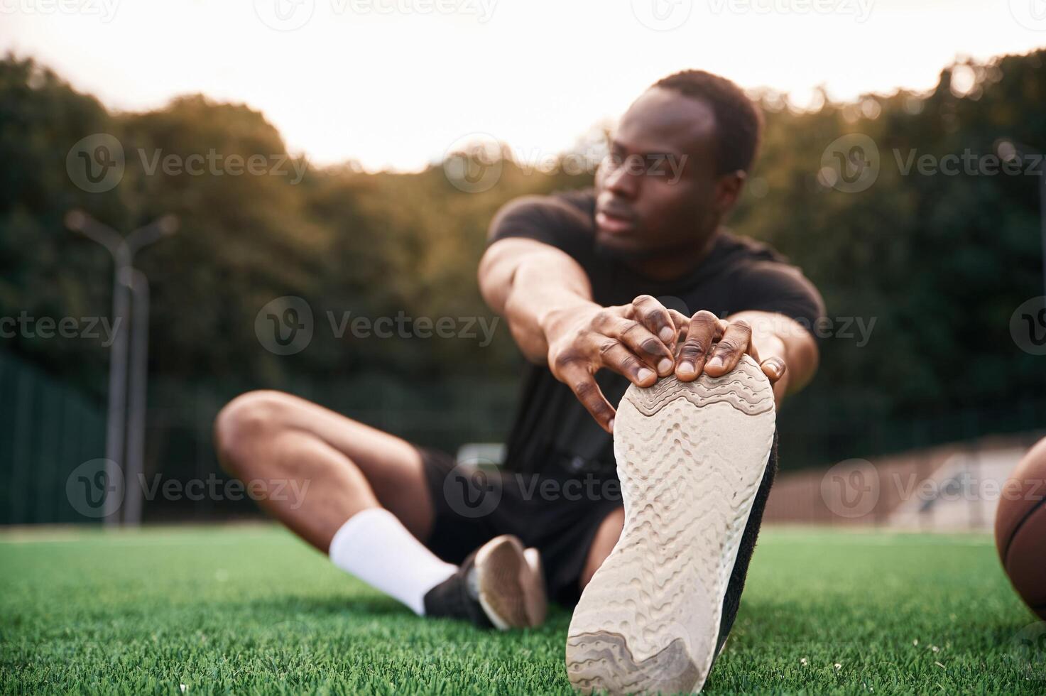 On ,the green ,court. Young black man is with basketball ball outdoors photo