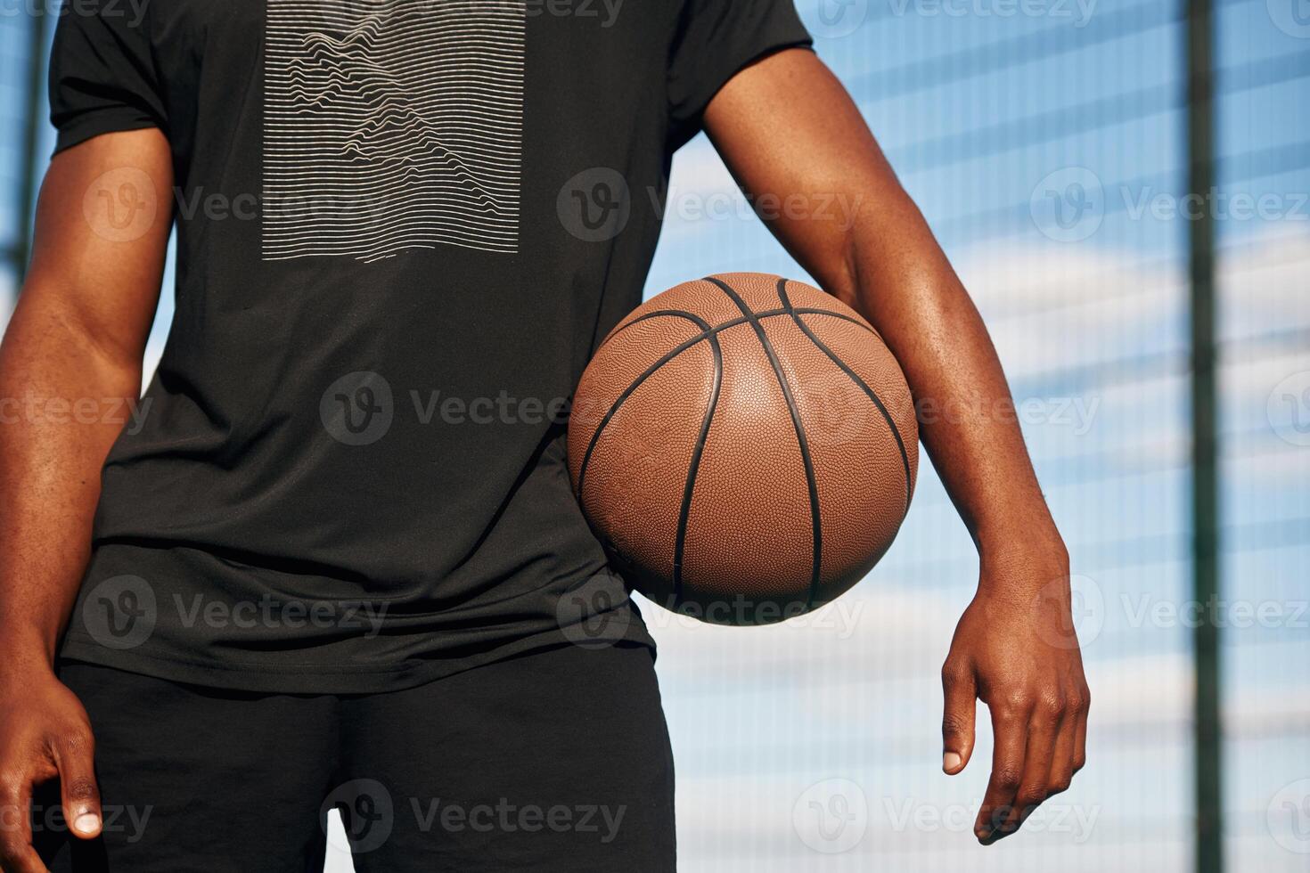 Close up view. Young black man is ,with basketball ball outdoors photo