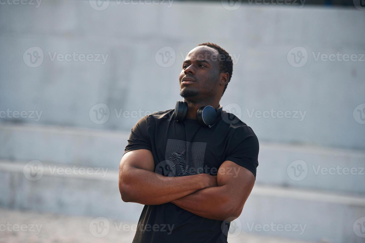 Standing, with arms crossed. Handsome black man is posing outdoors at daytime photo