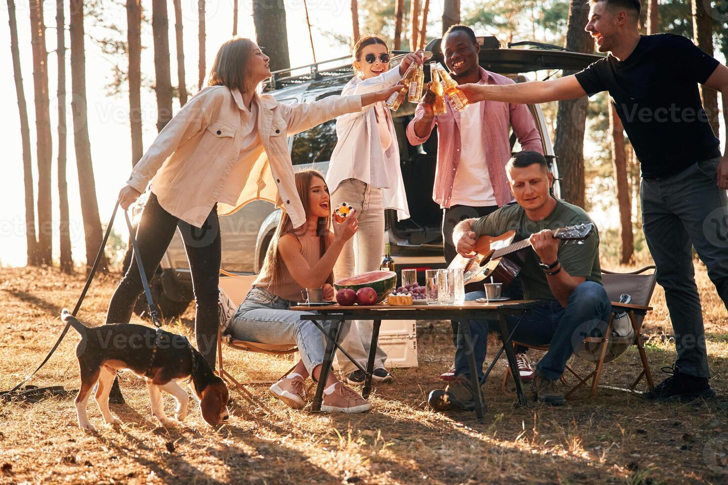 Doing cheers with bottles of beer.,, Group of friends are together in the forest photo