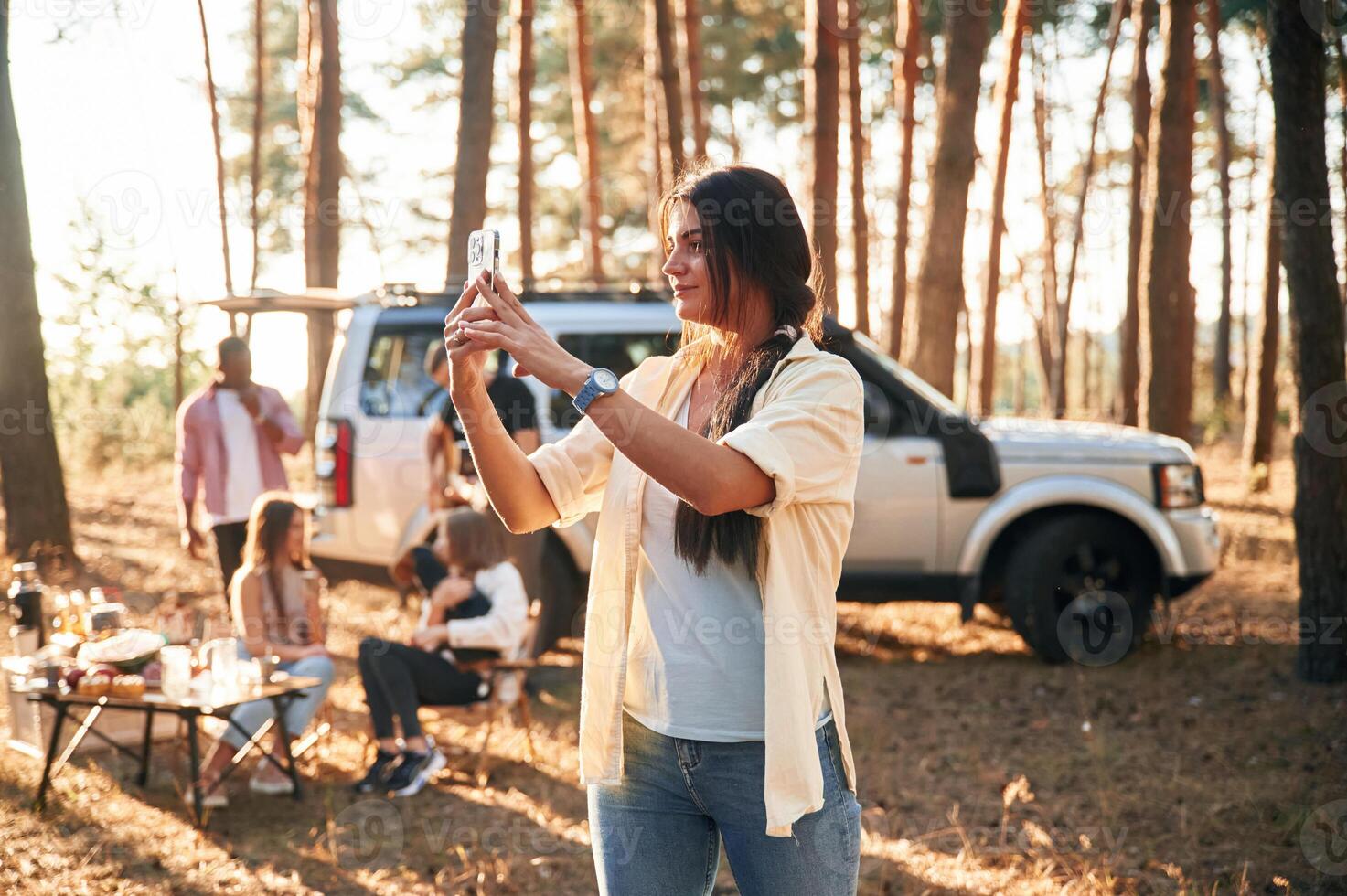 Woman is taking photo of nature. Group of friends are together in the ,forest