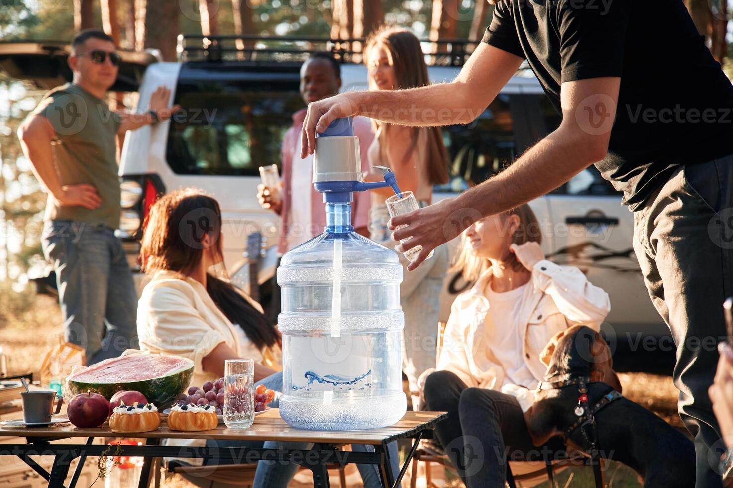 Pouring fresh water. Group, of friends are together in the forest photo