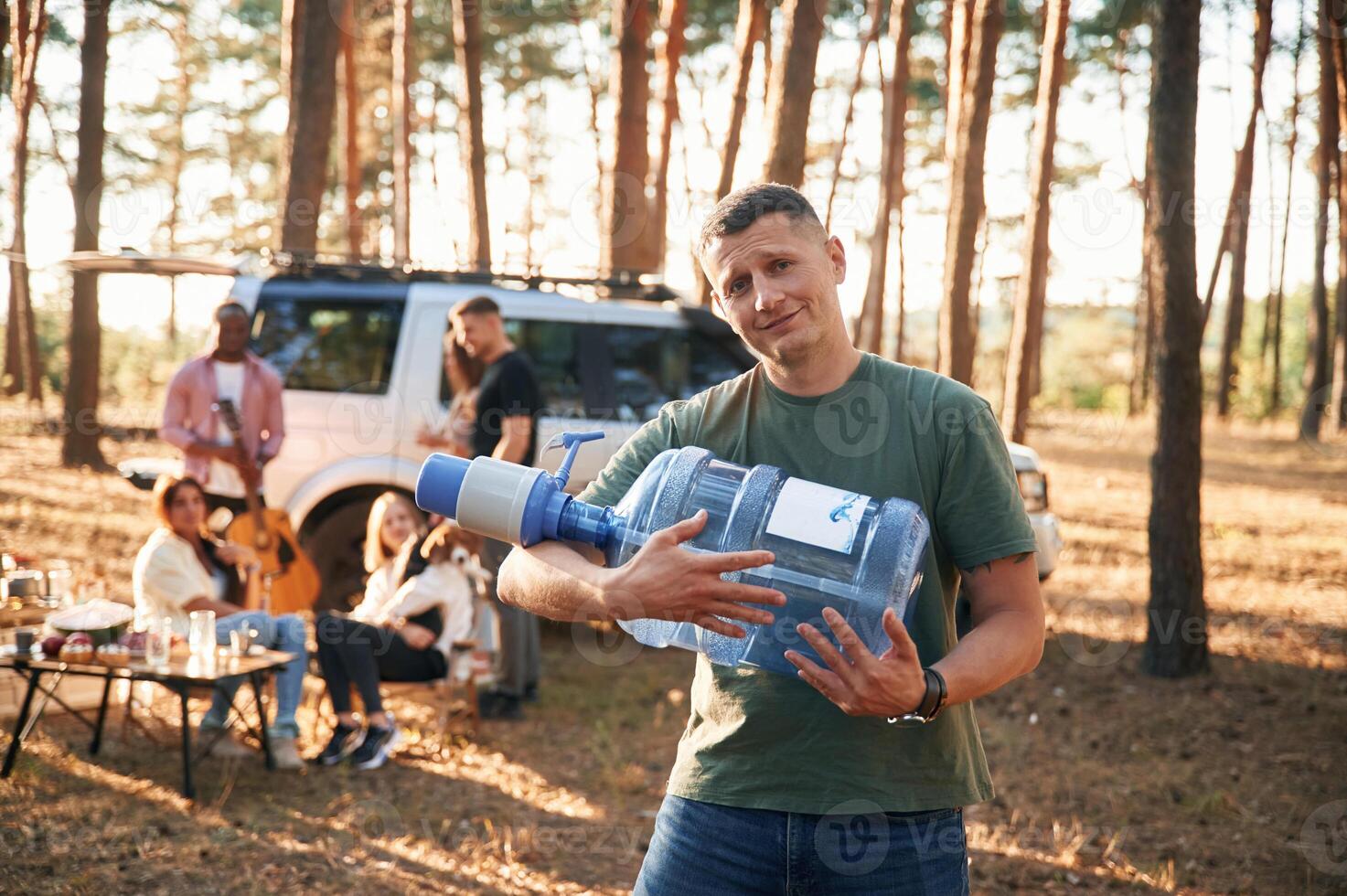 Man, with fresh water.. Group of friends are together in the forest photo