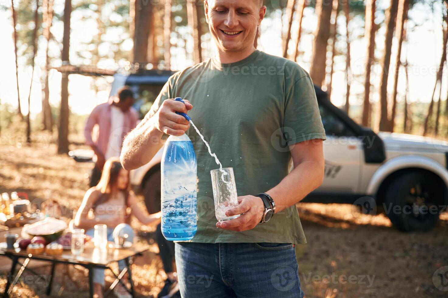 Man with fresh water. Group of, friends are together in the forest photo