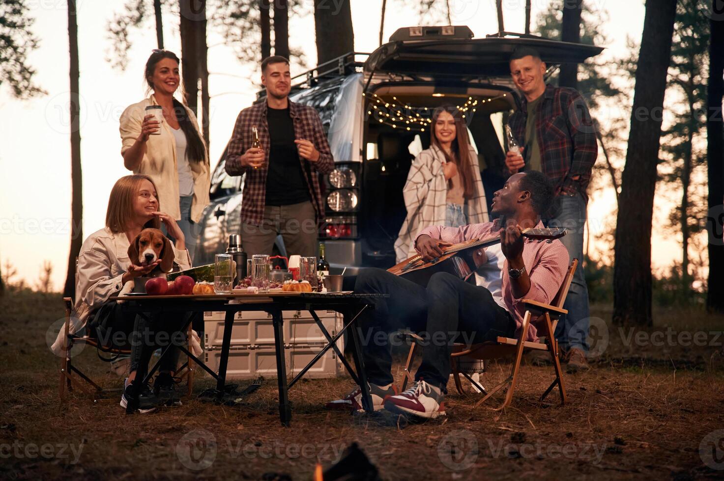 By the table at, evening time. Group of friends are together in the forest photo