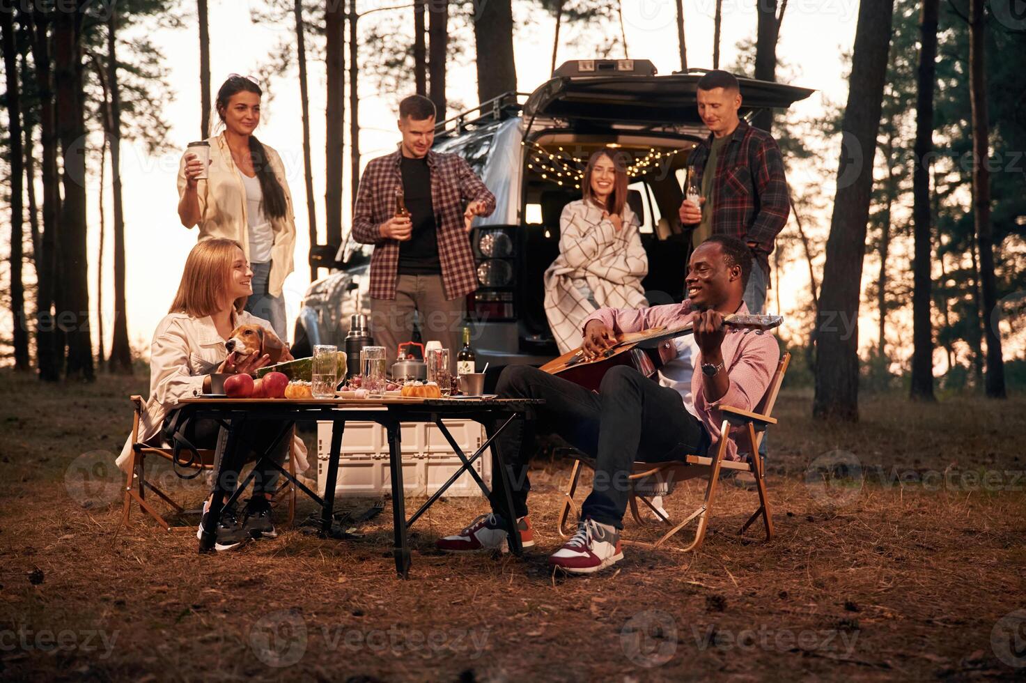 Evening time, by ,the table. Group of friends are together in the forest photo