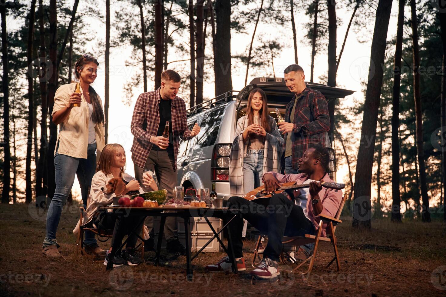 Evening time,, by the table. Group of friends are together in the forest photo