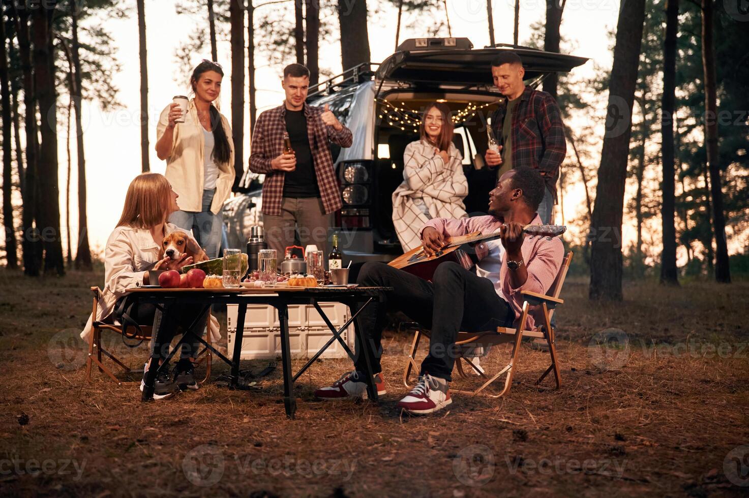 Evening, time,, by the table. Group of friends are together in the forest photo
