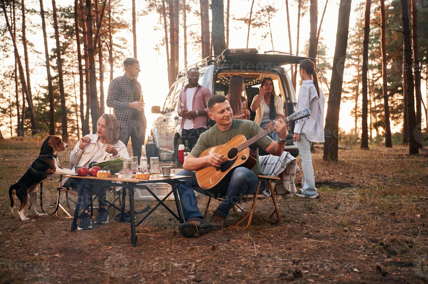 Acoustic, guitar player.. Group of friends are together in the forest photo