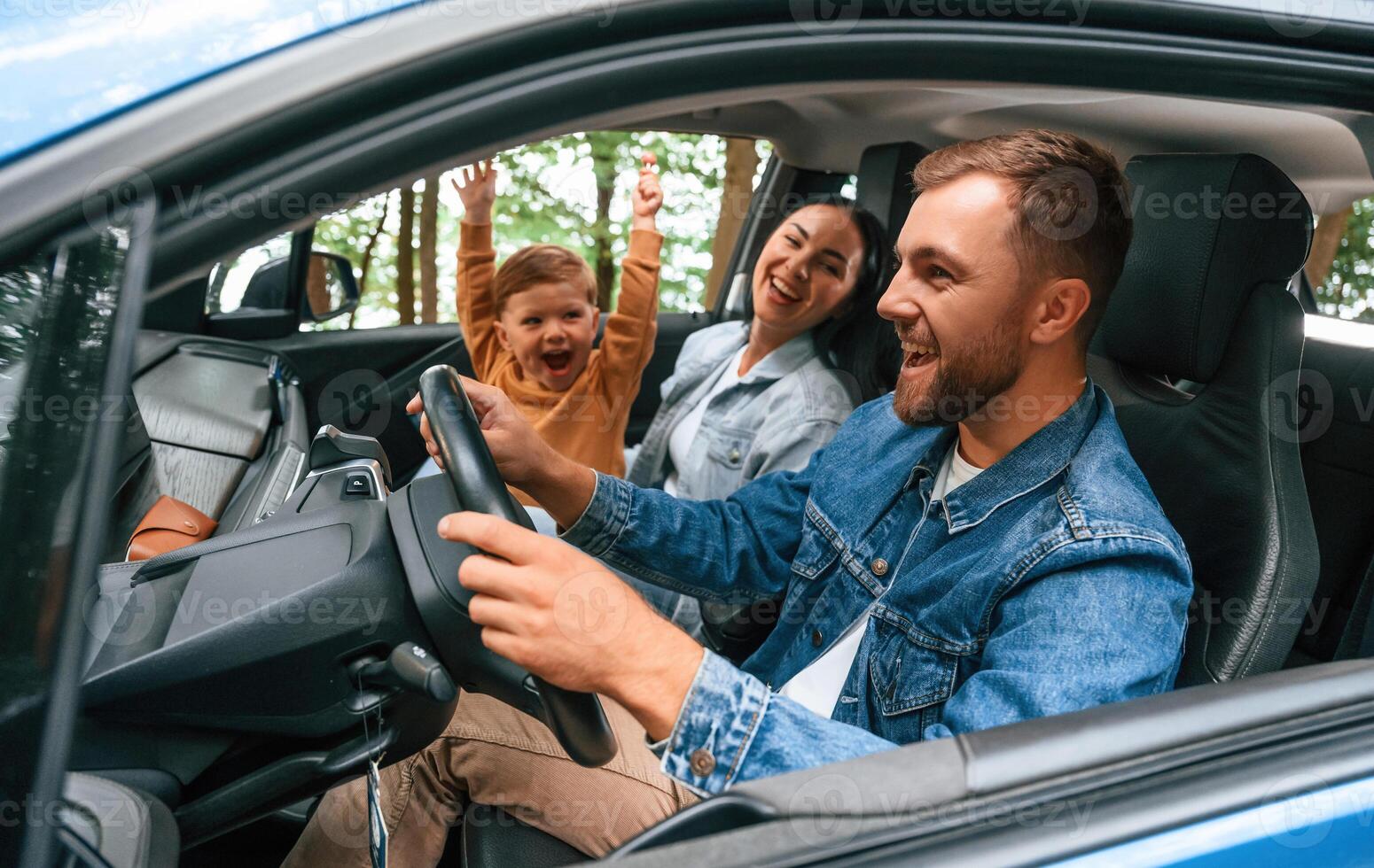On a ,trip. ,Family of father, mother and little son are sitting in the modern car photo