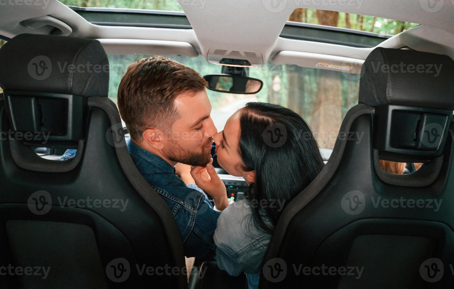 Rear view of the happy couple that are riding the car photo
