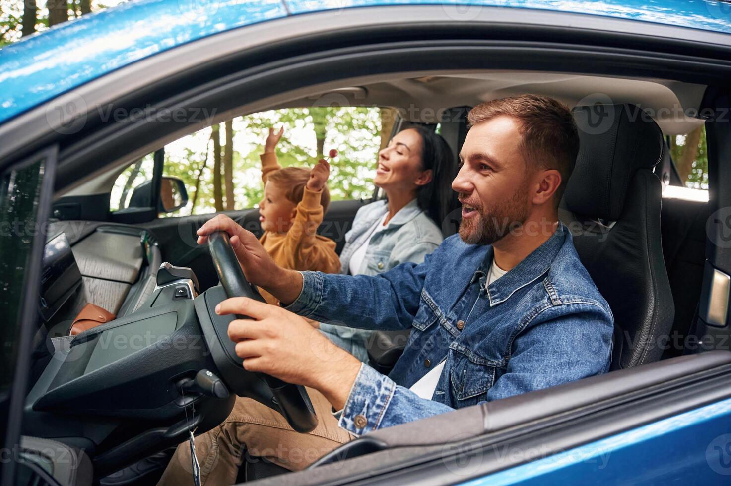 Side ,view, smiling... Family of father, mother and little son are sitting in the modern car photo