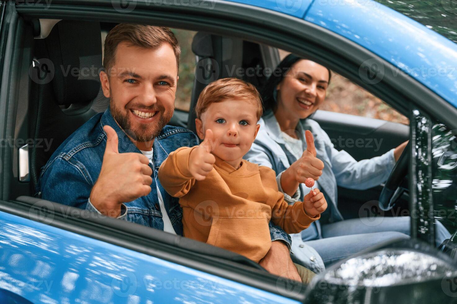 Family ,,of father, mother and little son are sitting in the modern car photo