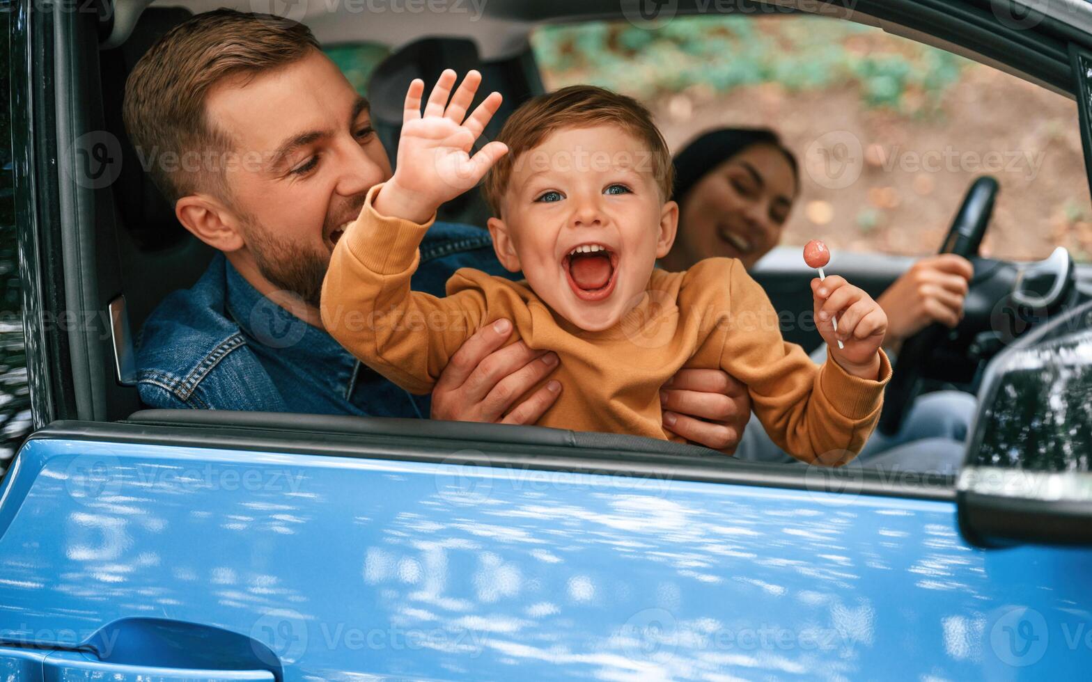 Family, of father, mother, and little son are sitting in the modern car photo