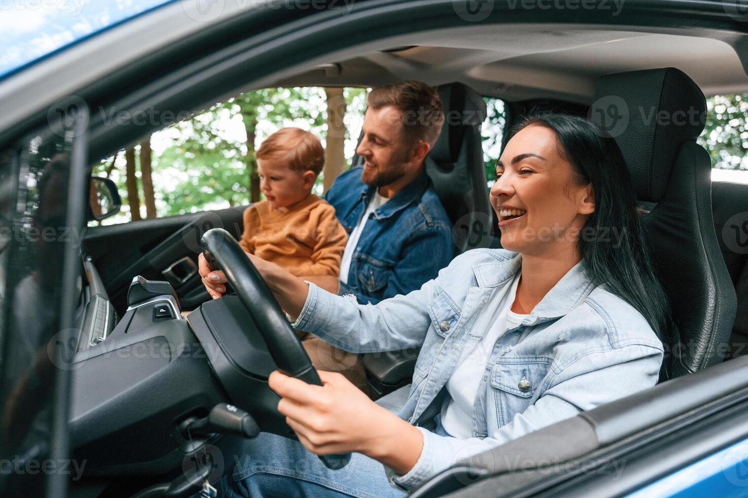 On a trip. .Family of father, mother and little son are sitting in the modern car photo