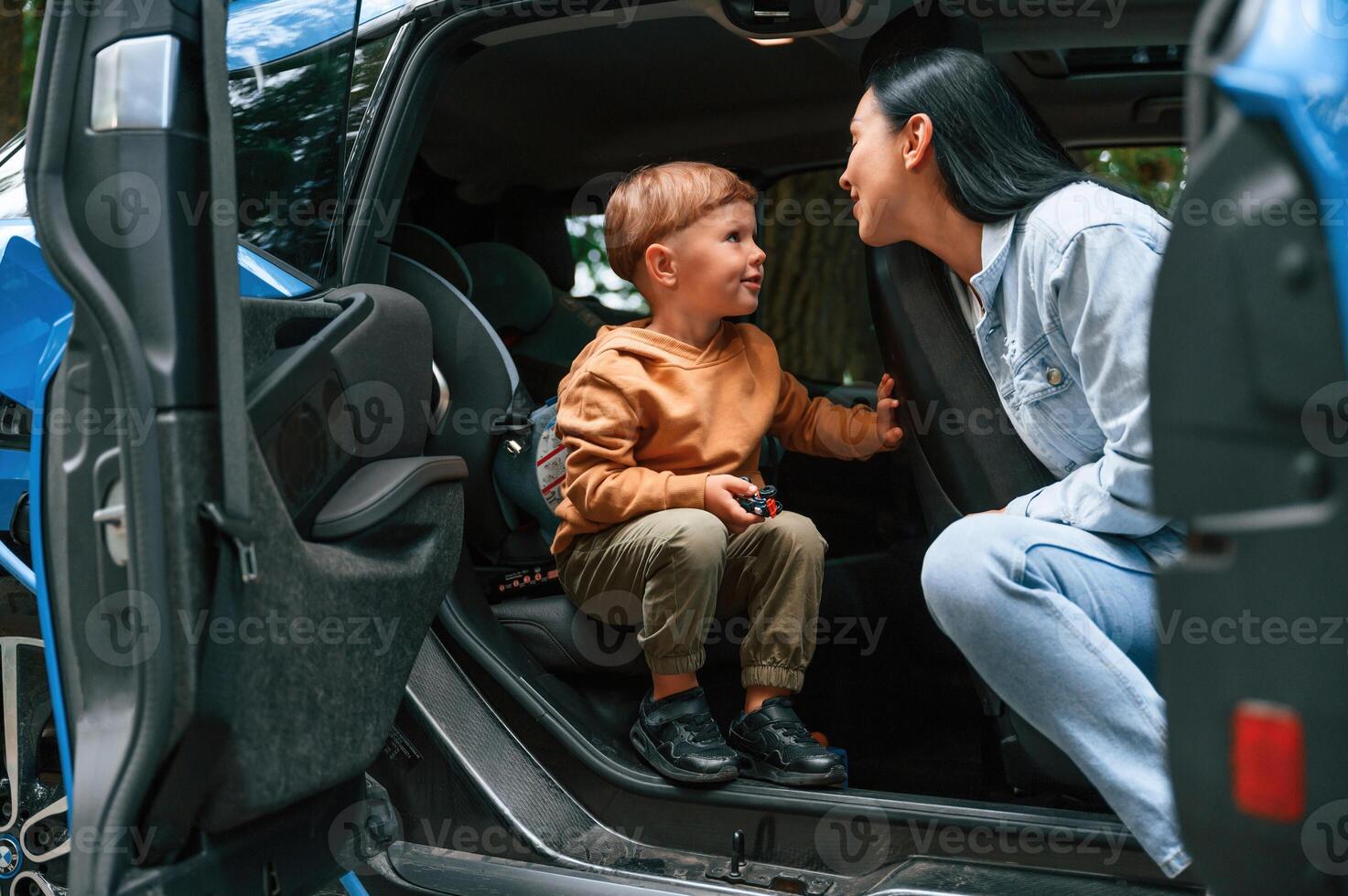 Mother with her little son are in the modern car, having fun photo