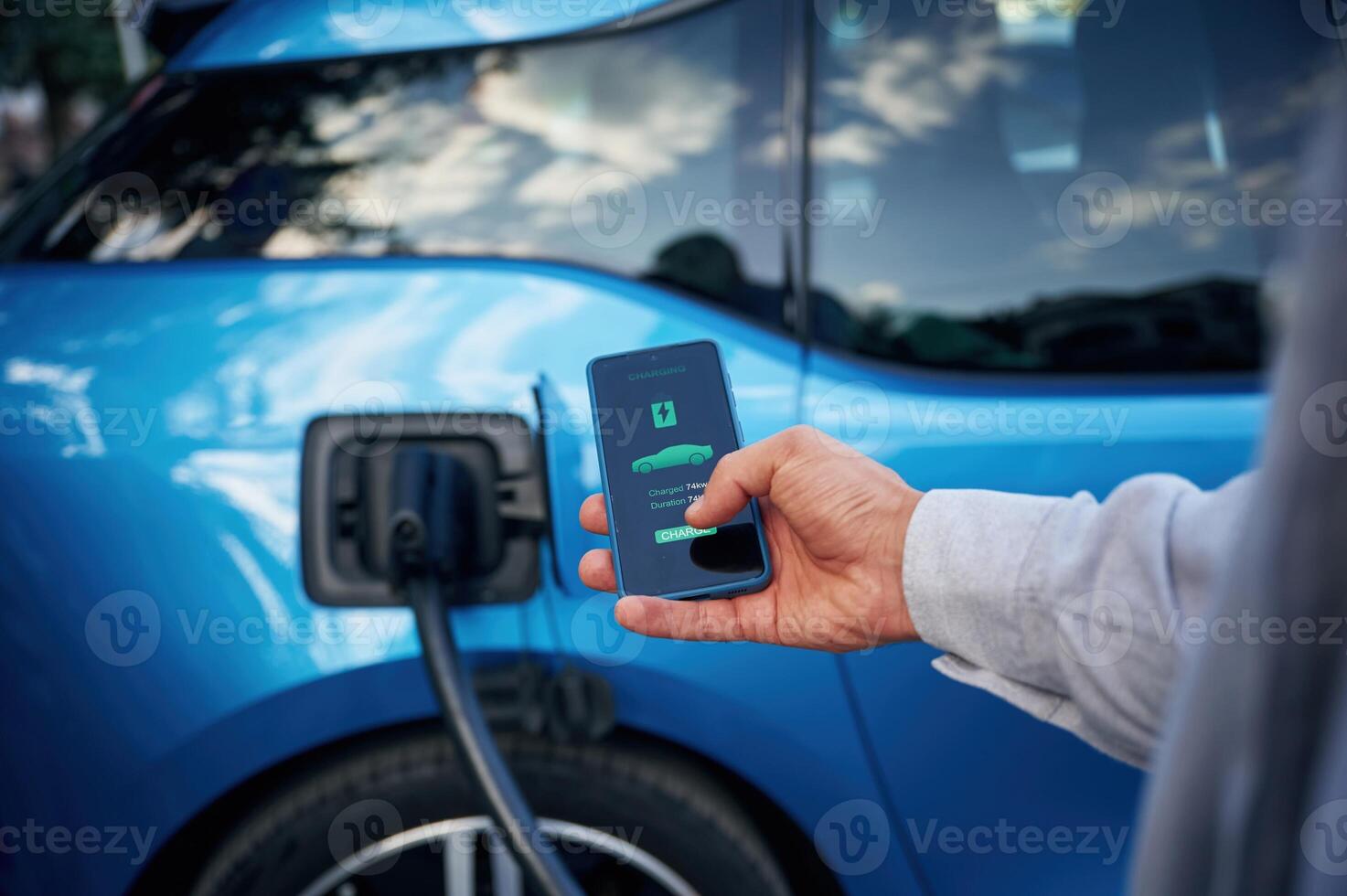 Showing, process ,on, the display of smartphone. Man with blue electric car on the charge station photo