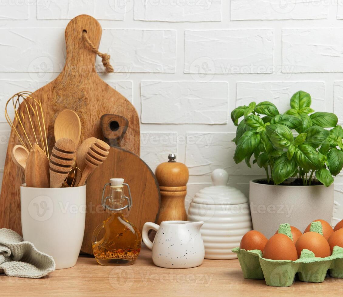Kitchen utensils, fresh eggs, basil plant and olive oil creating cozy atmosphere on wooden countertop photo