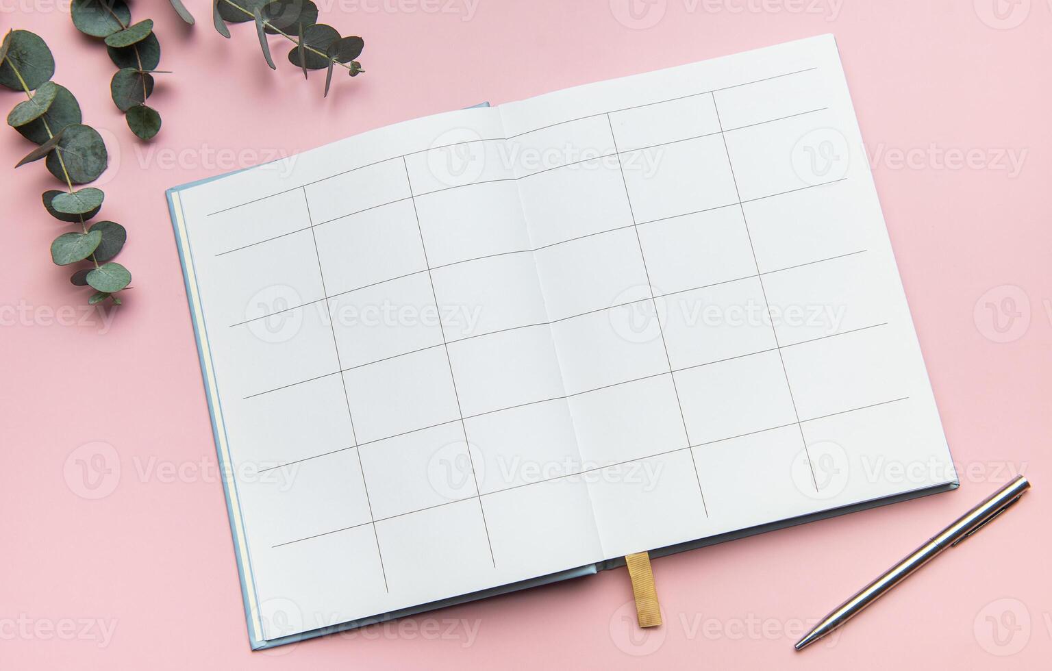 Open notebook showing blank pages with pen and eucalyptus leaves on pink background photo