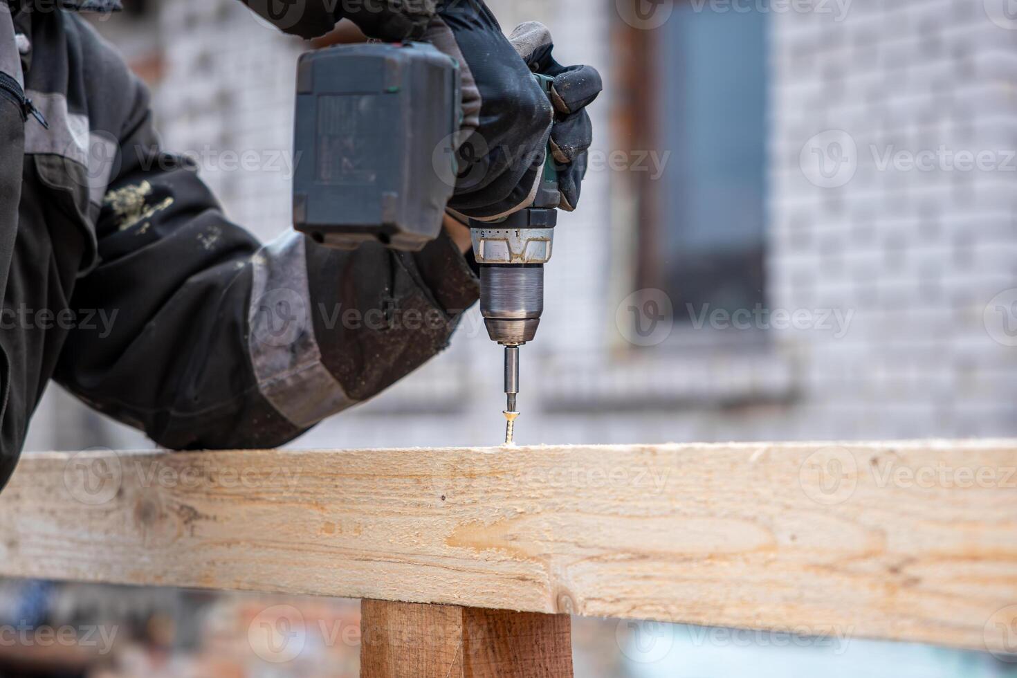 Worker Using Power Drill on Wooden Beam with Brick Building Background photo