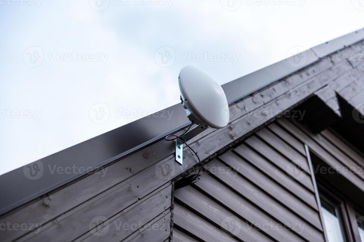 Modern WiFi Router on Wooden House with Overcast Sky photo
