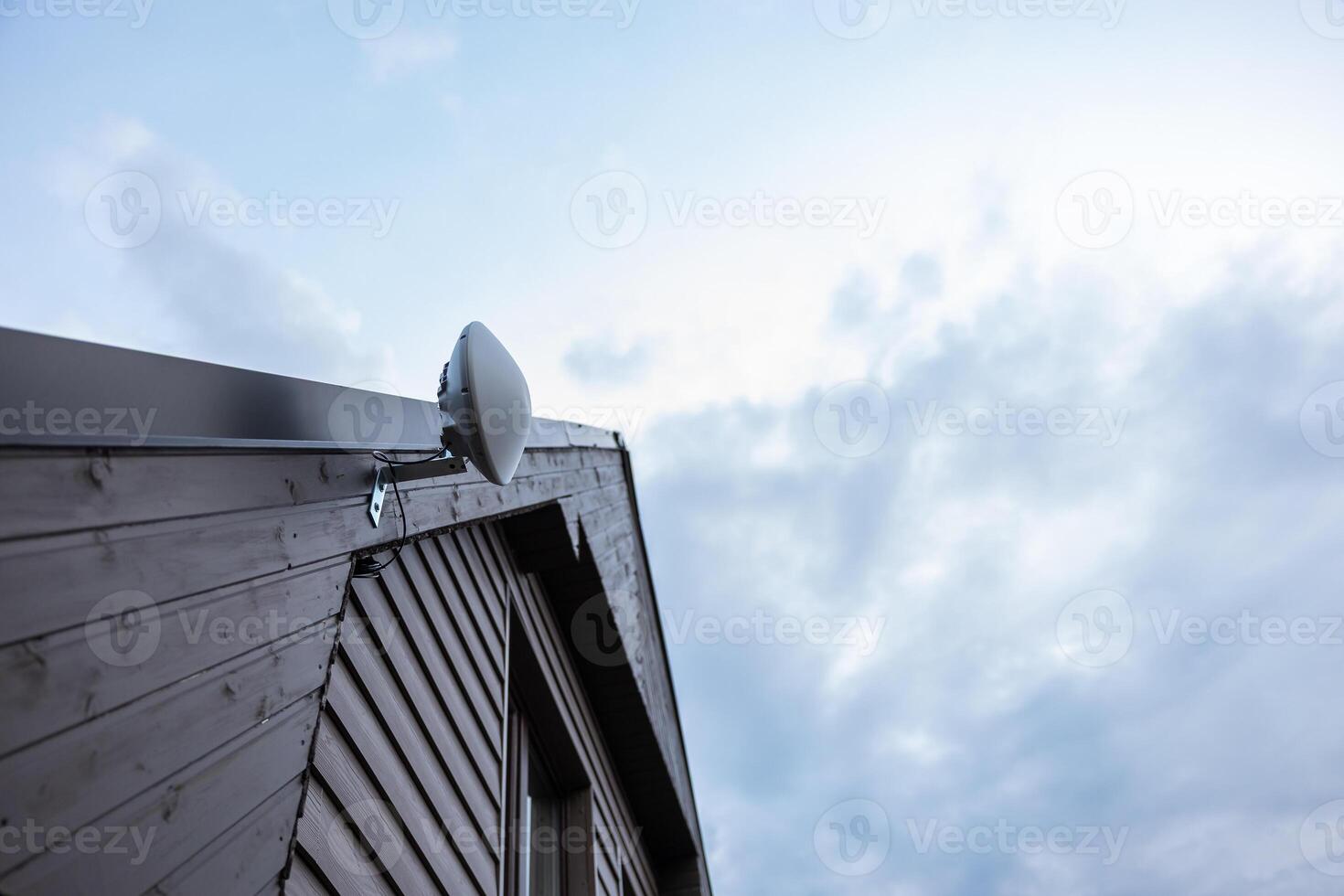 Wooden House Corner with Mounted White Wi Fi Router and Cloudy Sky photo