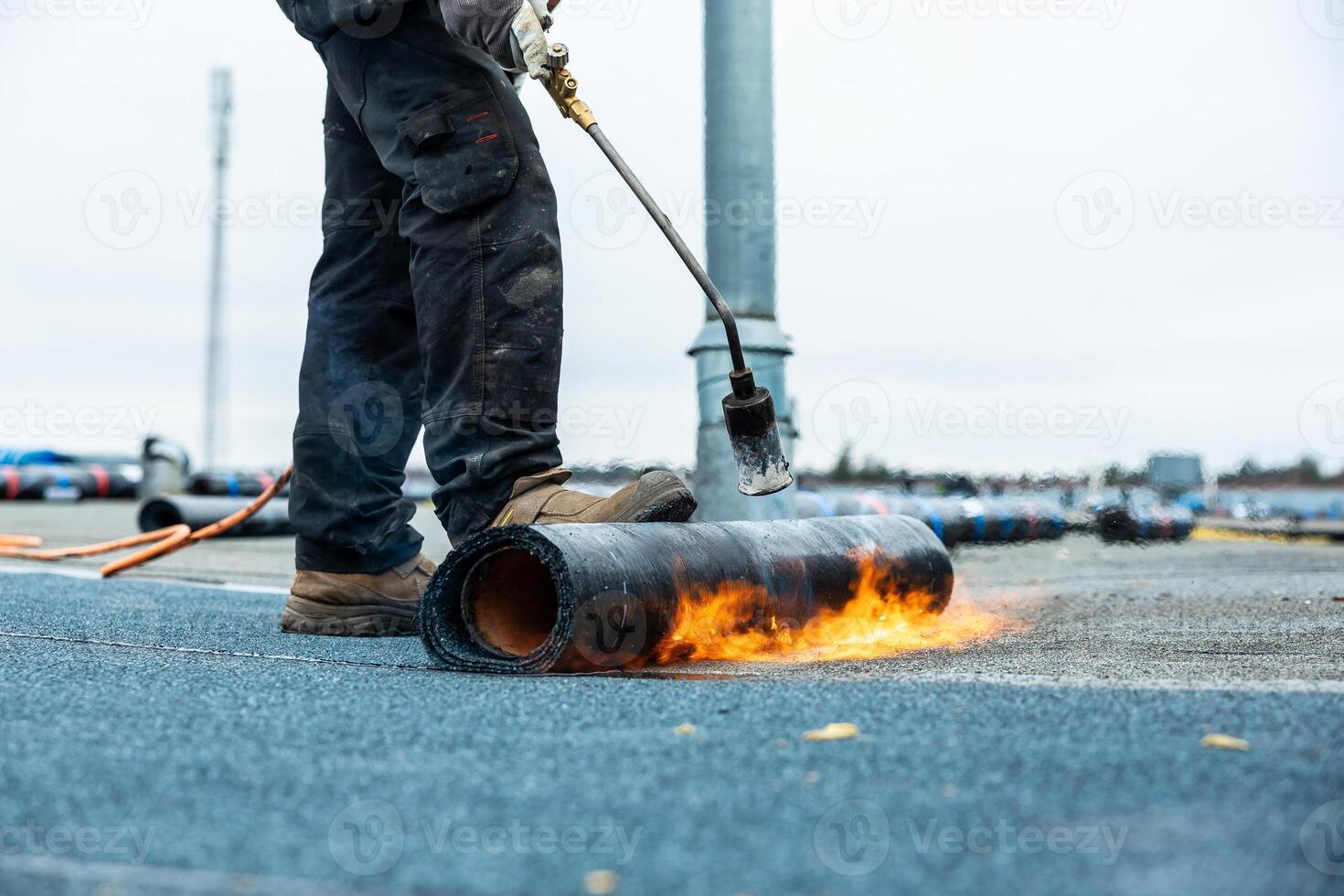Worker Using Torch to Apply Roofing Material on Flat Rooftop photo