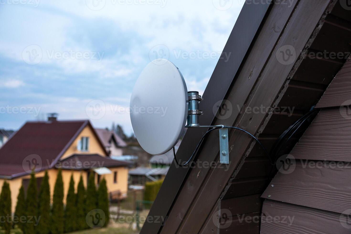 White Circular WiFi Antenna on Wooden House with Overcast Sky photo