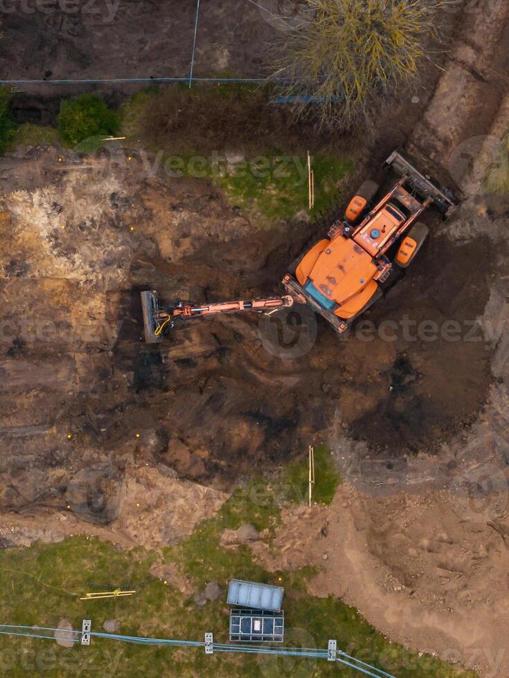 Aerial View of Excavator Operating on Construction Site with Soil and Grass photo