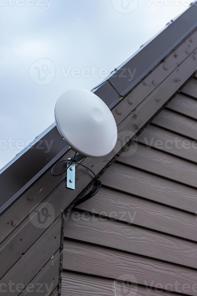 Circular White Wi Fi Router Mounted on Wooden Siding of Private House photo