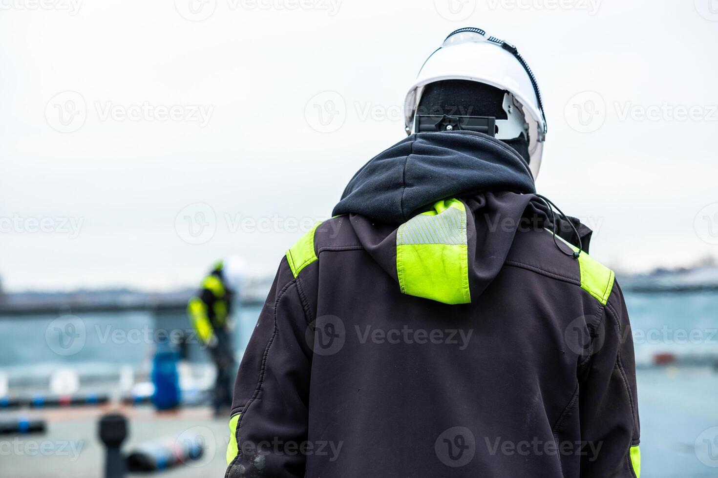 Workers in Safety Gear on Rooftop with Urban Skyline in Background photo