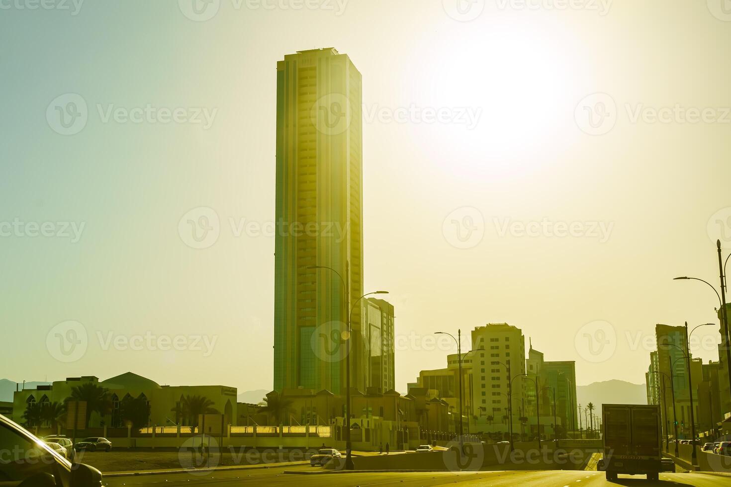A car driving down a street with a tall building in the background photo