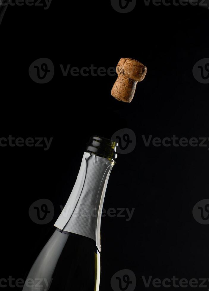 Celebration unfolds as cork pops from sparkling beverage bottle amidst backdrop photo