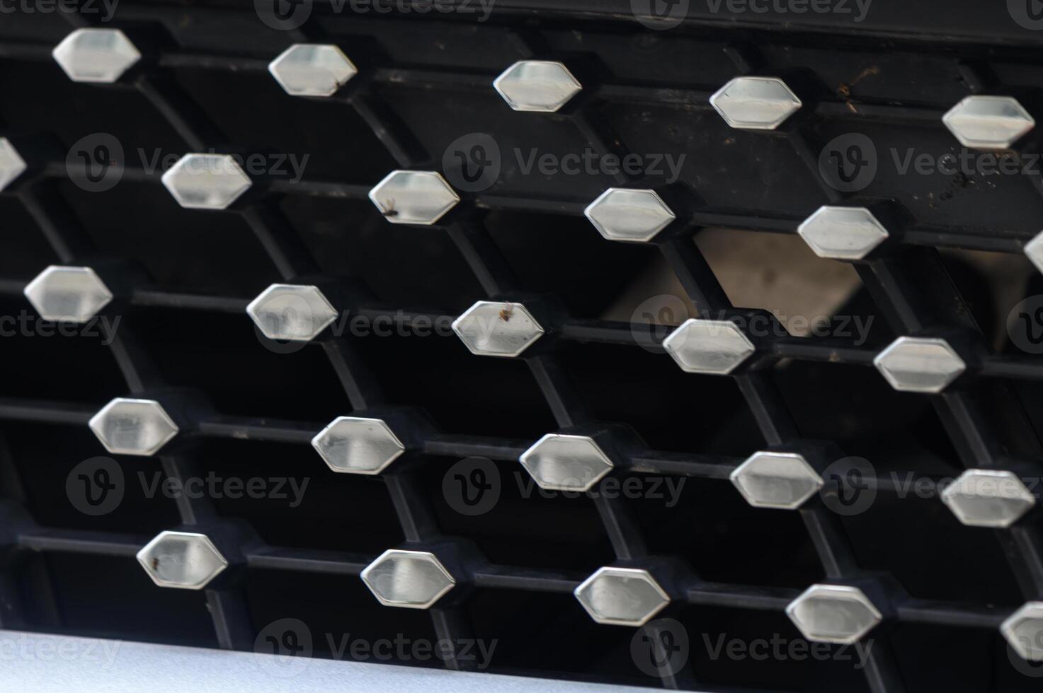 Intricate Pattern of Metallic Hexagons on a Black Grille in Natural Light photo
