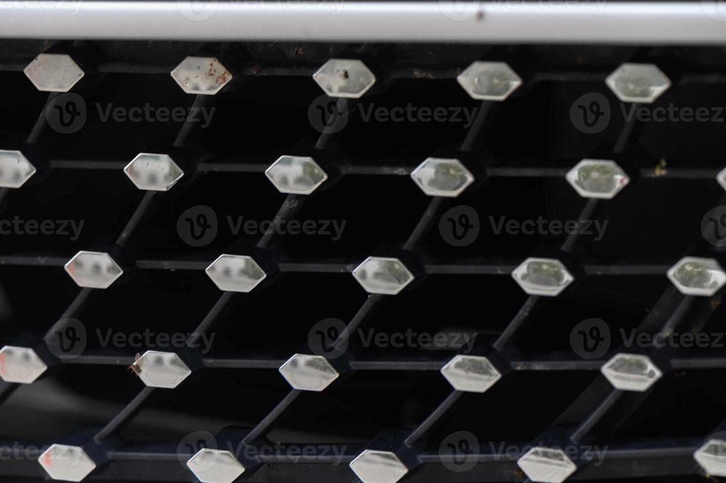 Close-up view of an intricate car grille design showcasing geometric patterns and textures in a modern aesthetic photo