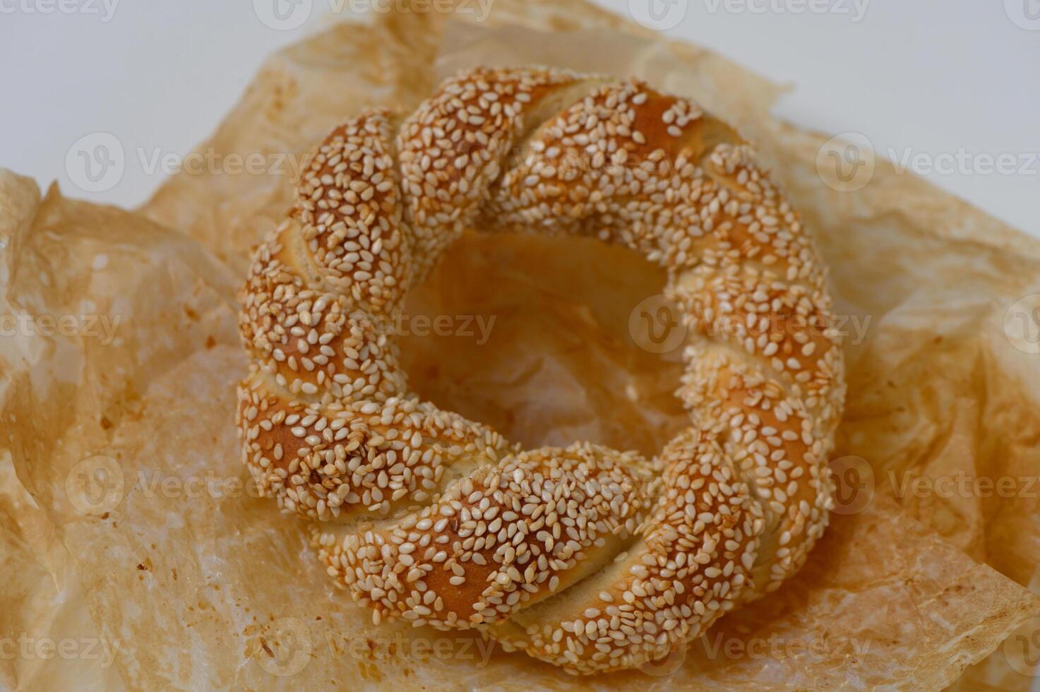 Freshly baked sesame bread ring rests on parchment paper, showcasing its golden brown crust and delicate texture, ready to be enjoyed photo