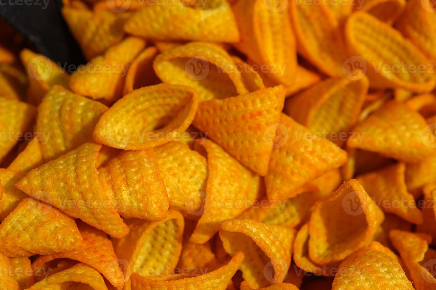 Colorful and crispy conical snacks are piled high in a vibrant food market bustling with energy and tantalizing aromas photo