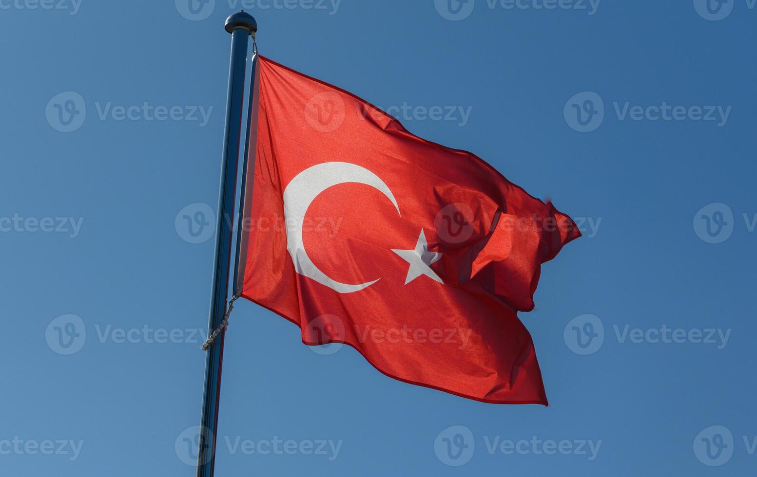 Vibrant Turkish flag waving proudly against a clear blue sky in a sunlit outdoor setting photo