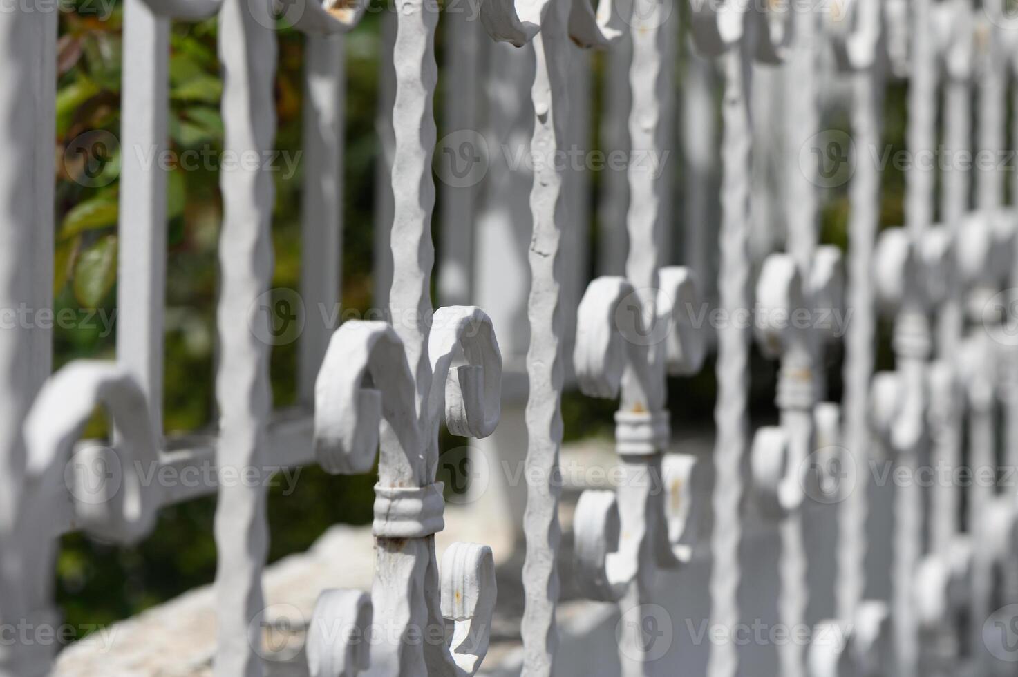 Curved white iron railing details spark imagination with intricate design elements in a sunlit garden setting photo