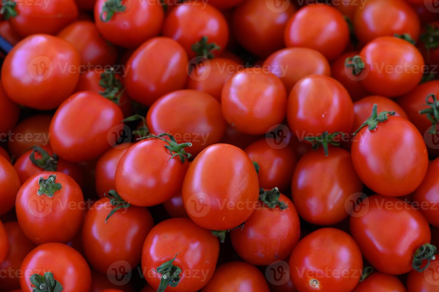 Vibrant red tomatoes piled high at a bustling farmers market, inviting shoppers on a sunny afternoon photo