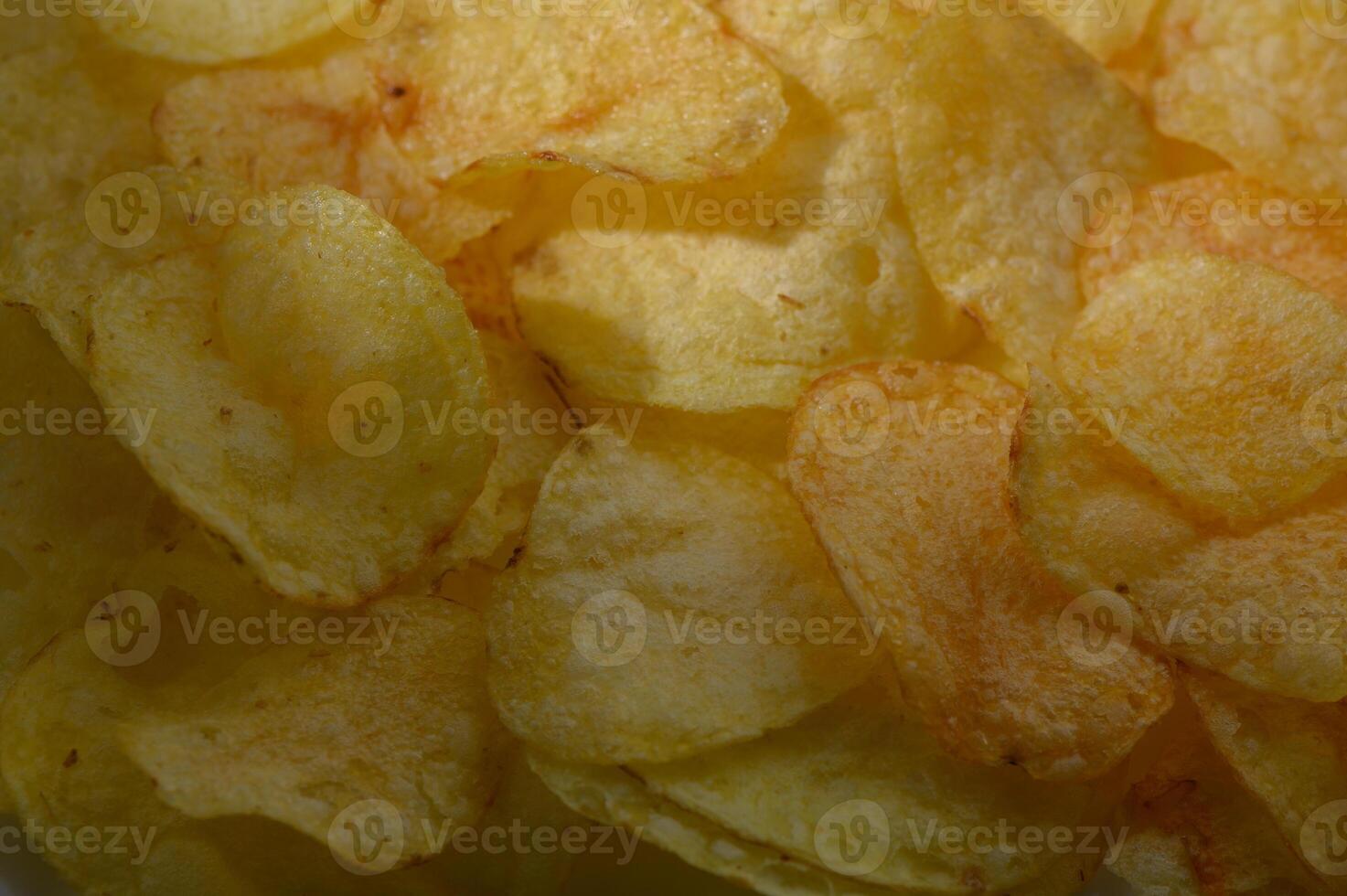 Crunchy potato chips glisten with golden hues in a close-up view showcasing their delightful texture and flavor photo